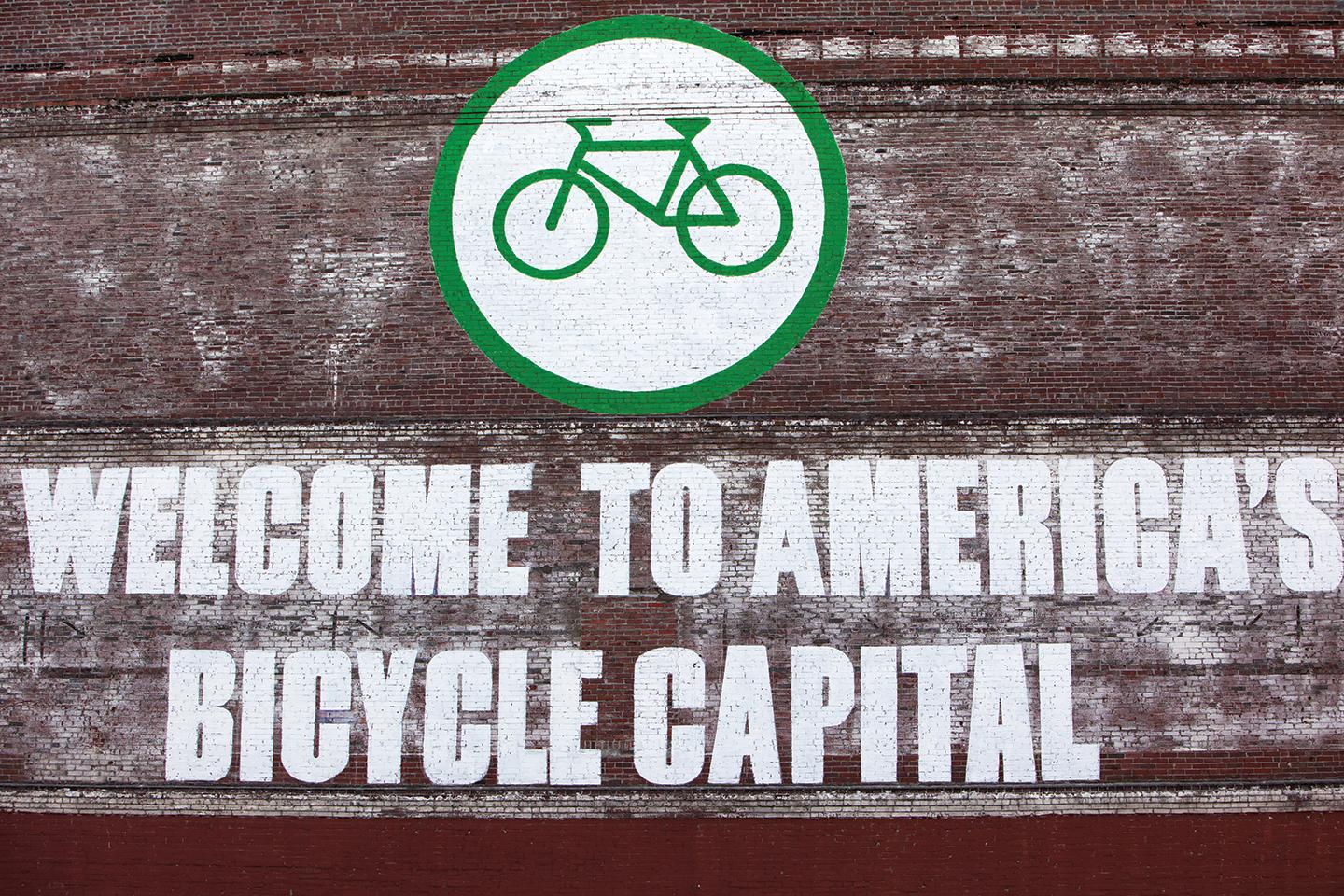 Picture of a sign reading "Welcome to America's Bicycle capital" with a small image of a green bike against a white circular background.