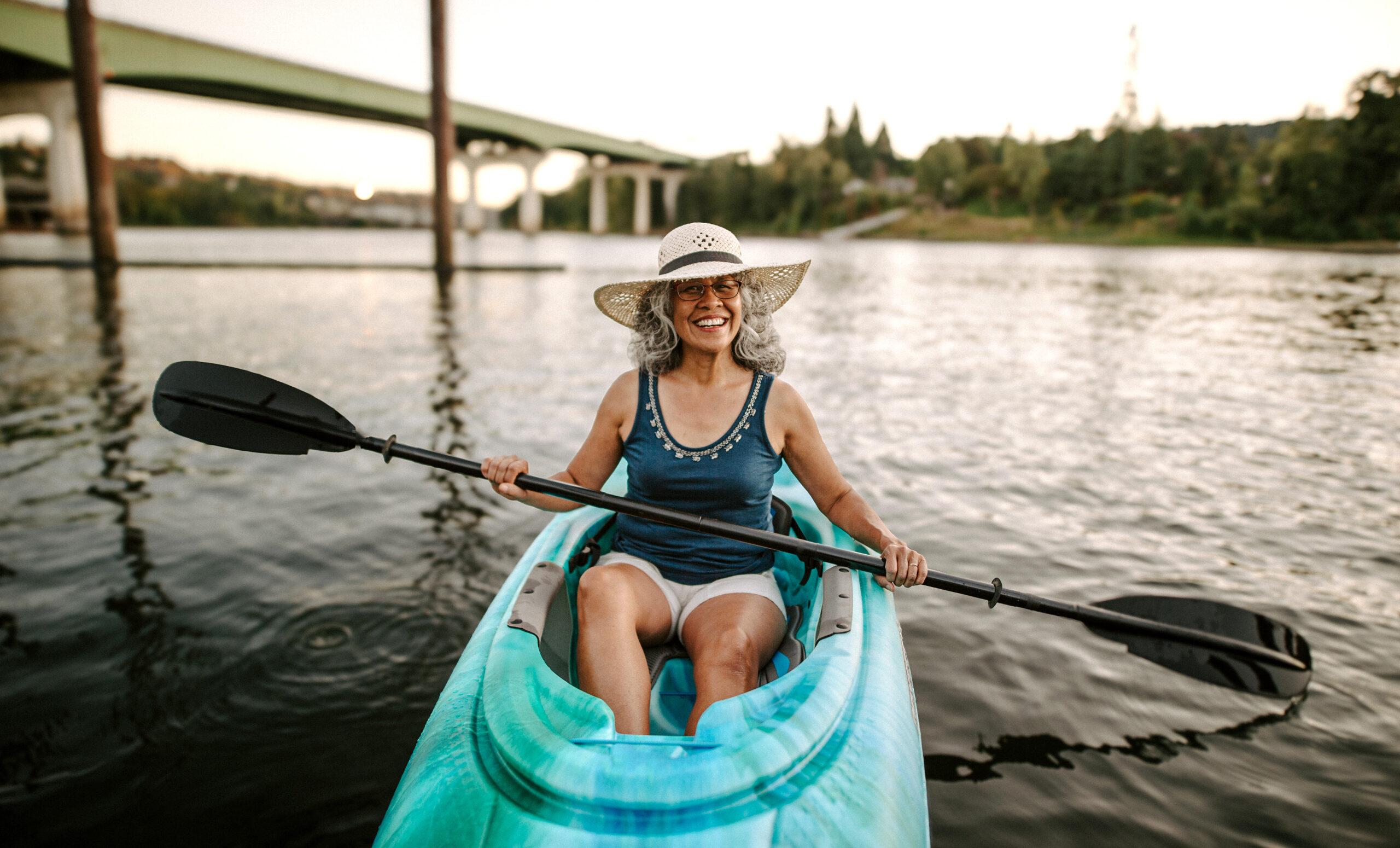 Smiling Pacific Islander senior woman kayaking.