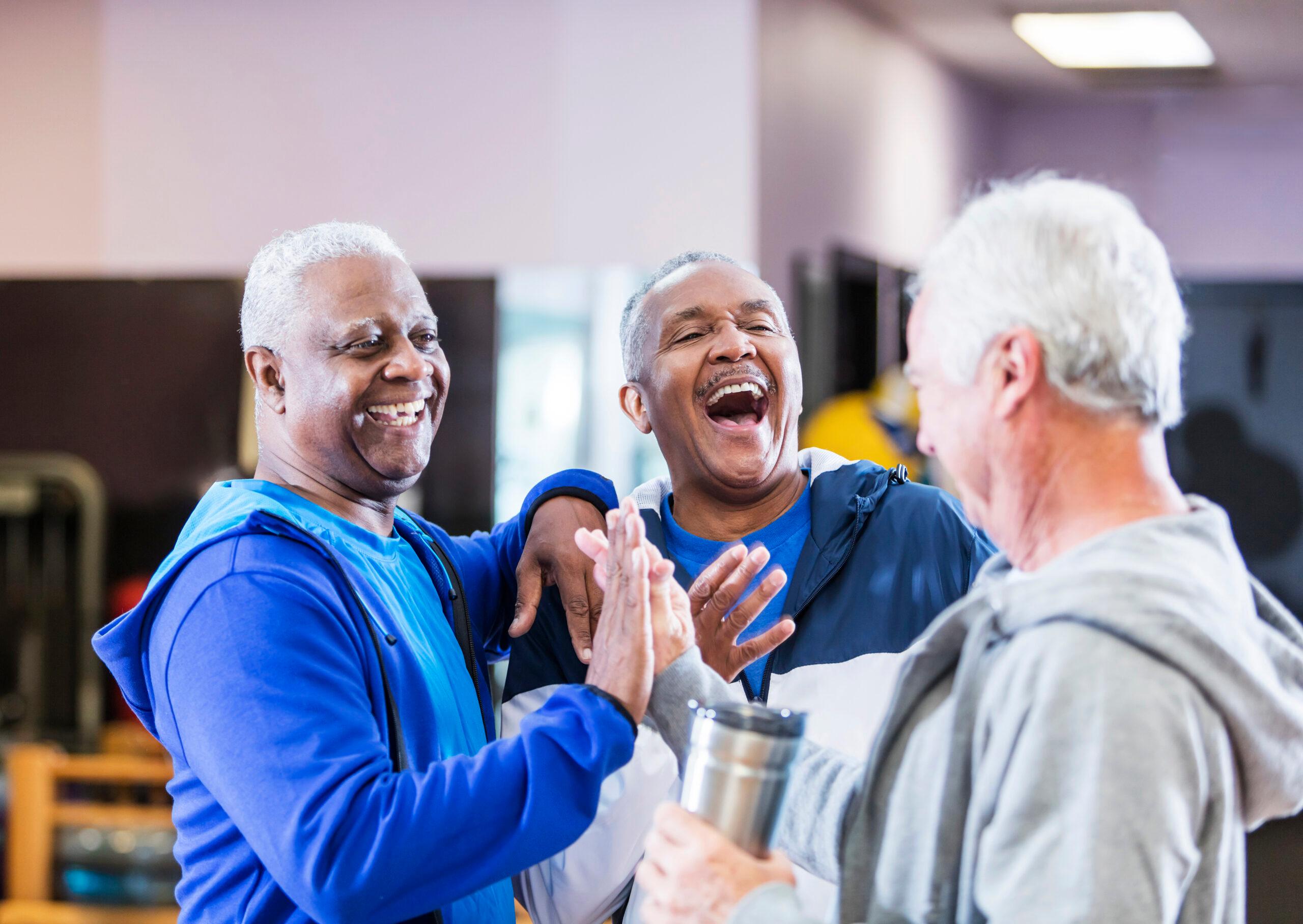 Three men hanging out at gym, talking and laughing.