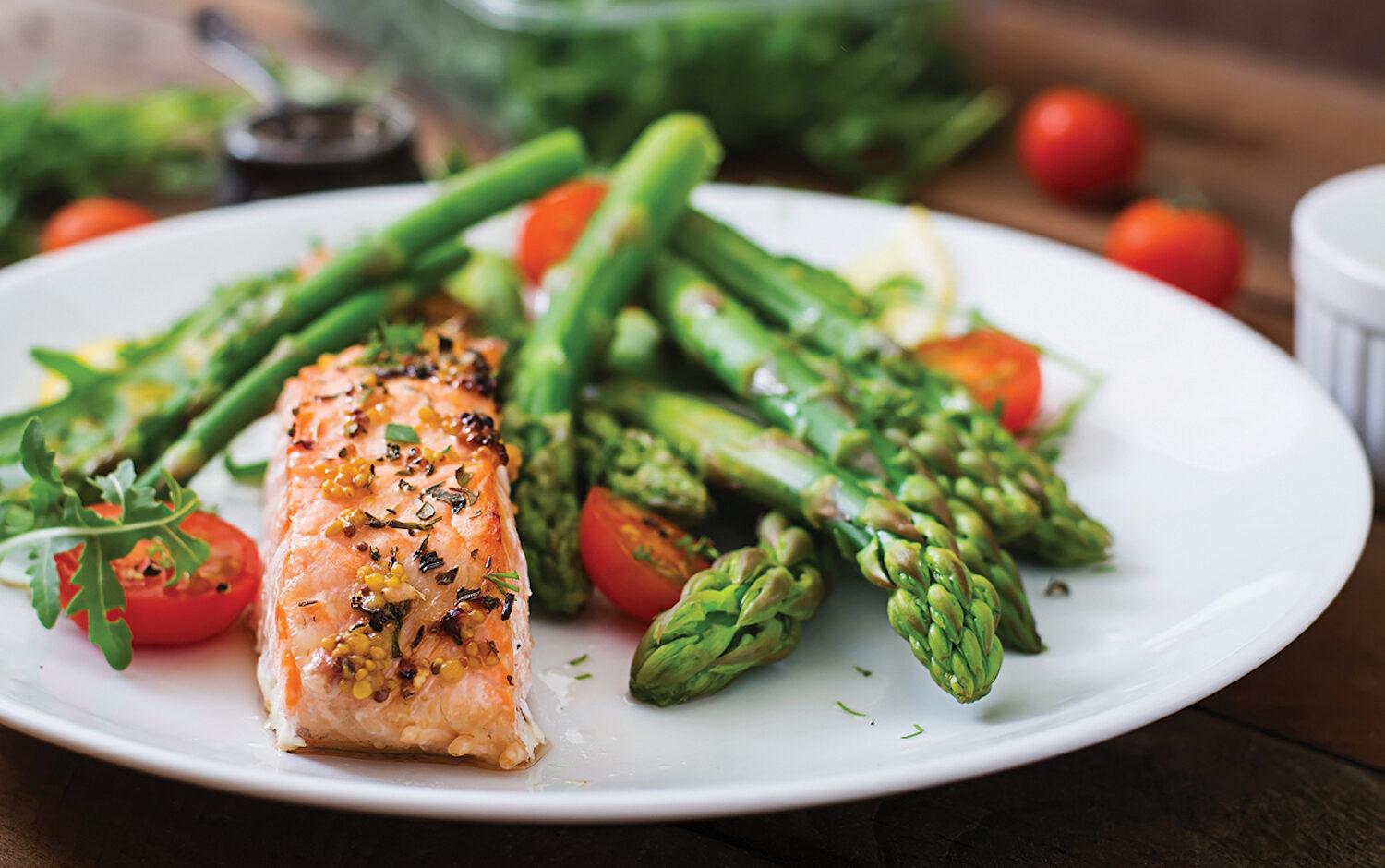 Baked salmon garnished with asparagus and tomatoes with herbs.