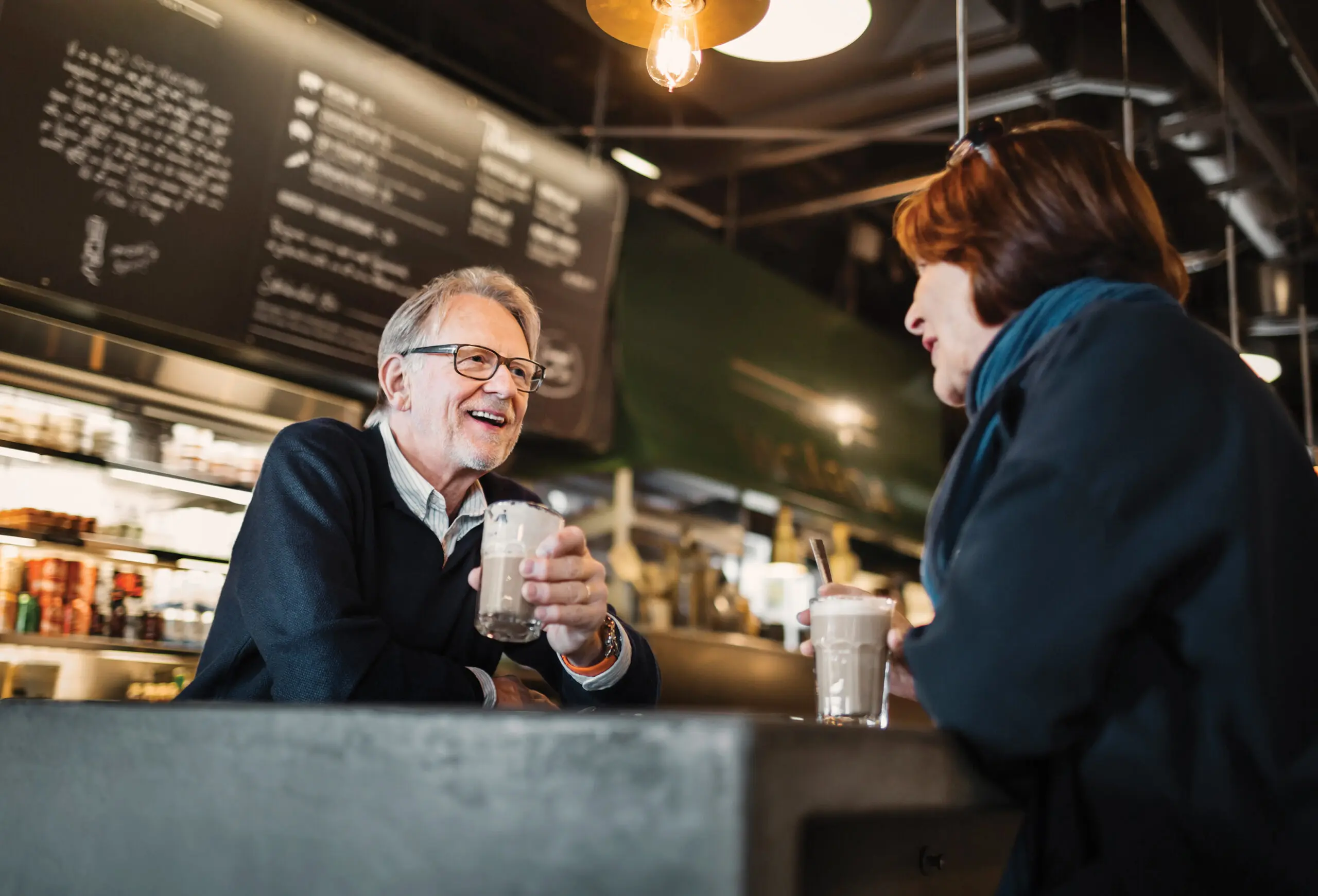 Low-angle shot of two older adults have an interesting conversation at a coffee shop.