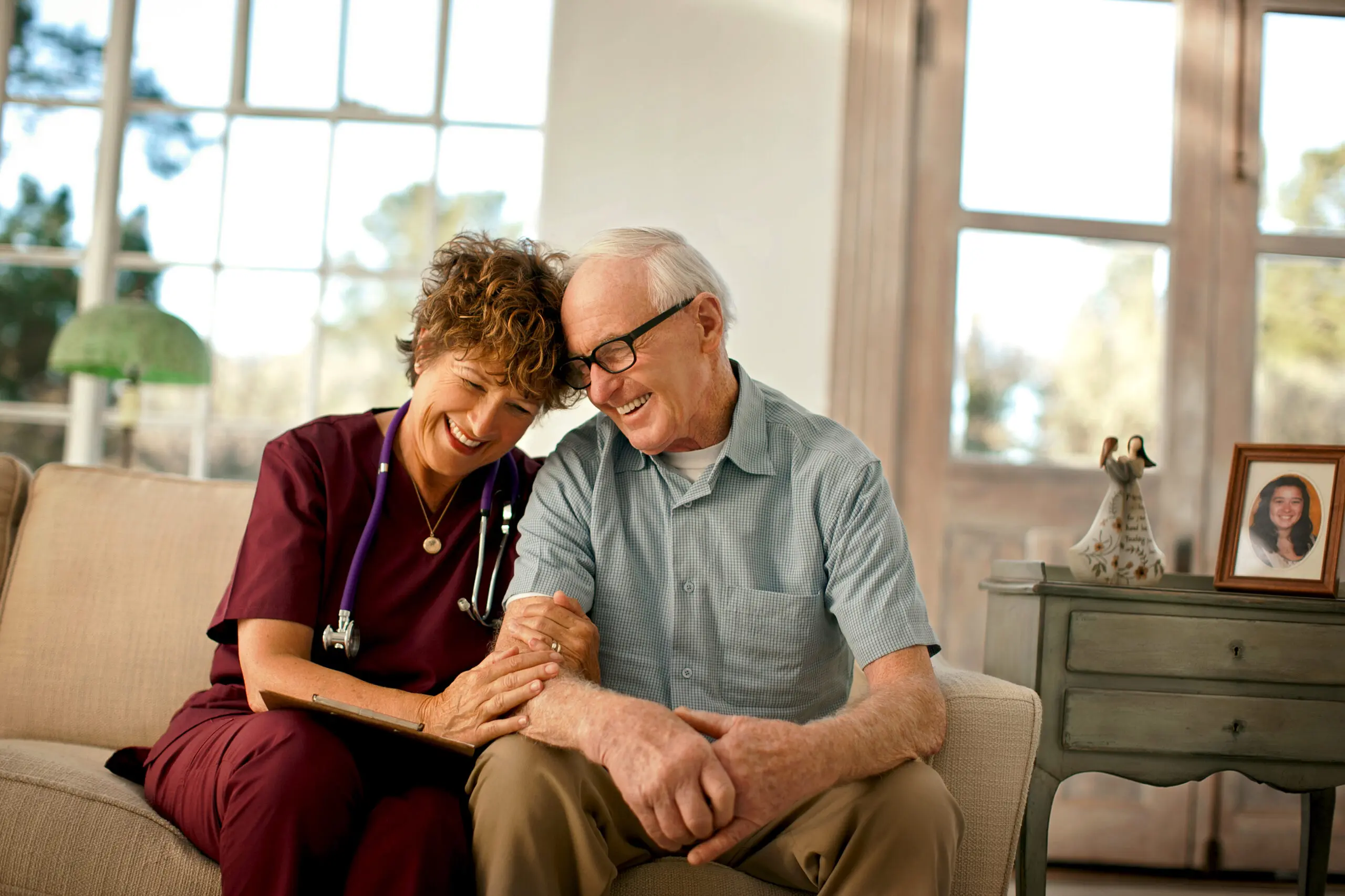 A smiling home care nurse comforts a patient.